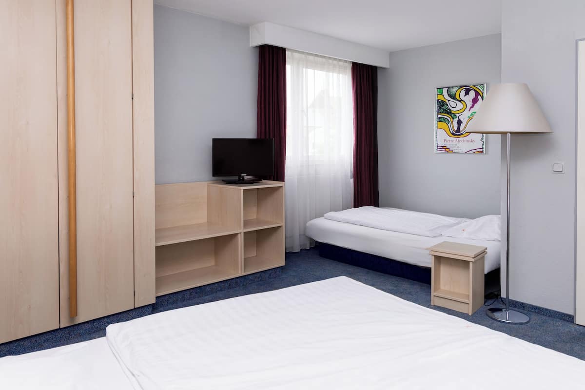 Ein Hotelzimmer mit Bett, Fernseher, Schreibtisch und Lampe.