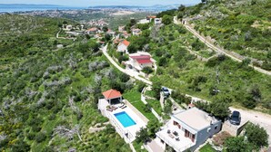A hillside property with a swimming pool, a modern house, and a view of a coastal town. - Nice home in Zrnovnica (Zrnovnica)