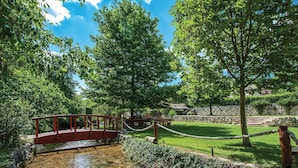 A park with a red bridge, stone walls, and a grassy area with trees. - Nice home in Zrnovnica (Zrnovnica)