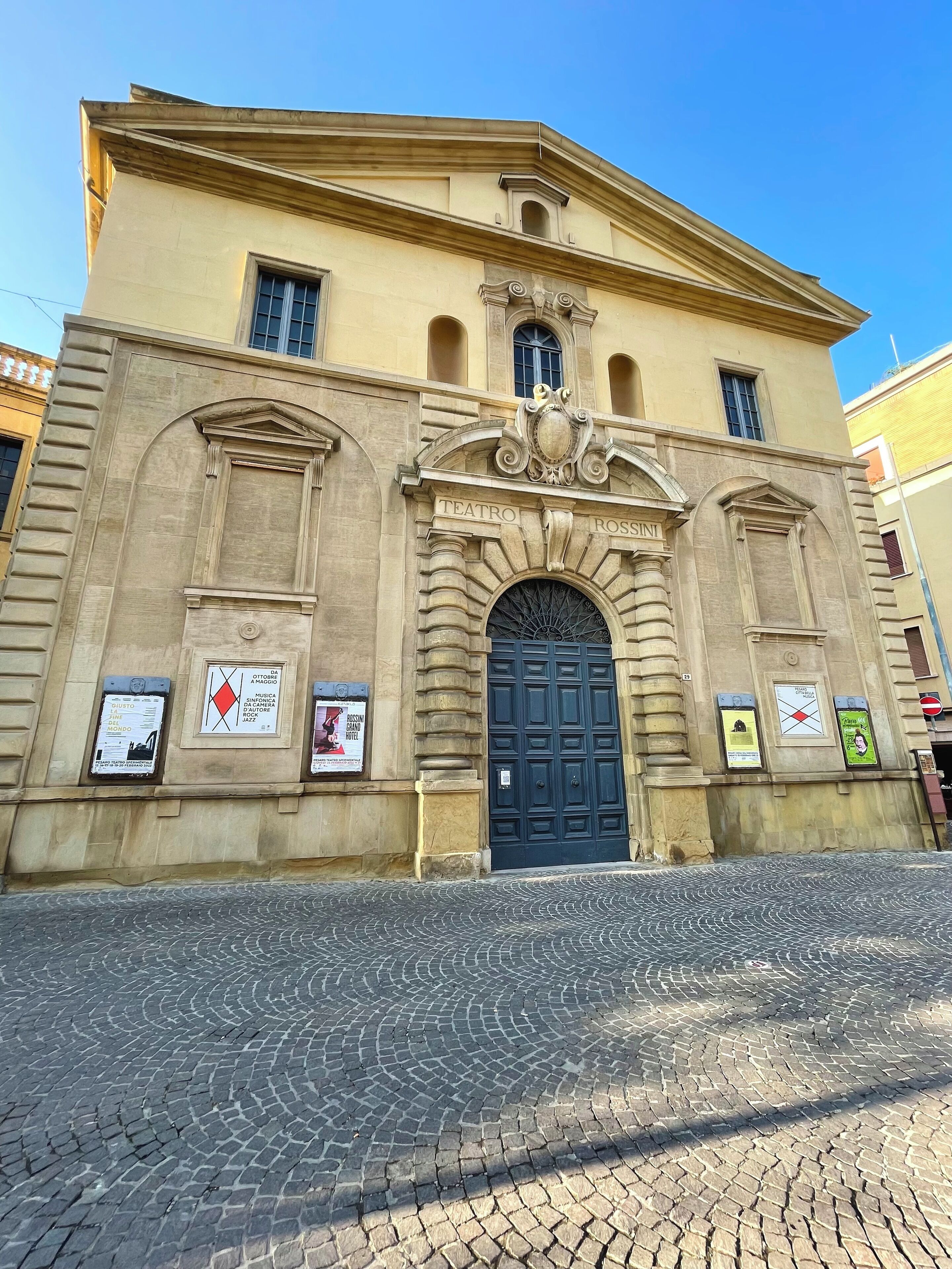 A historic building with a prominent entrance, a clock, and a plaque.
