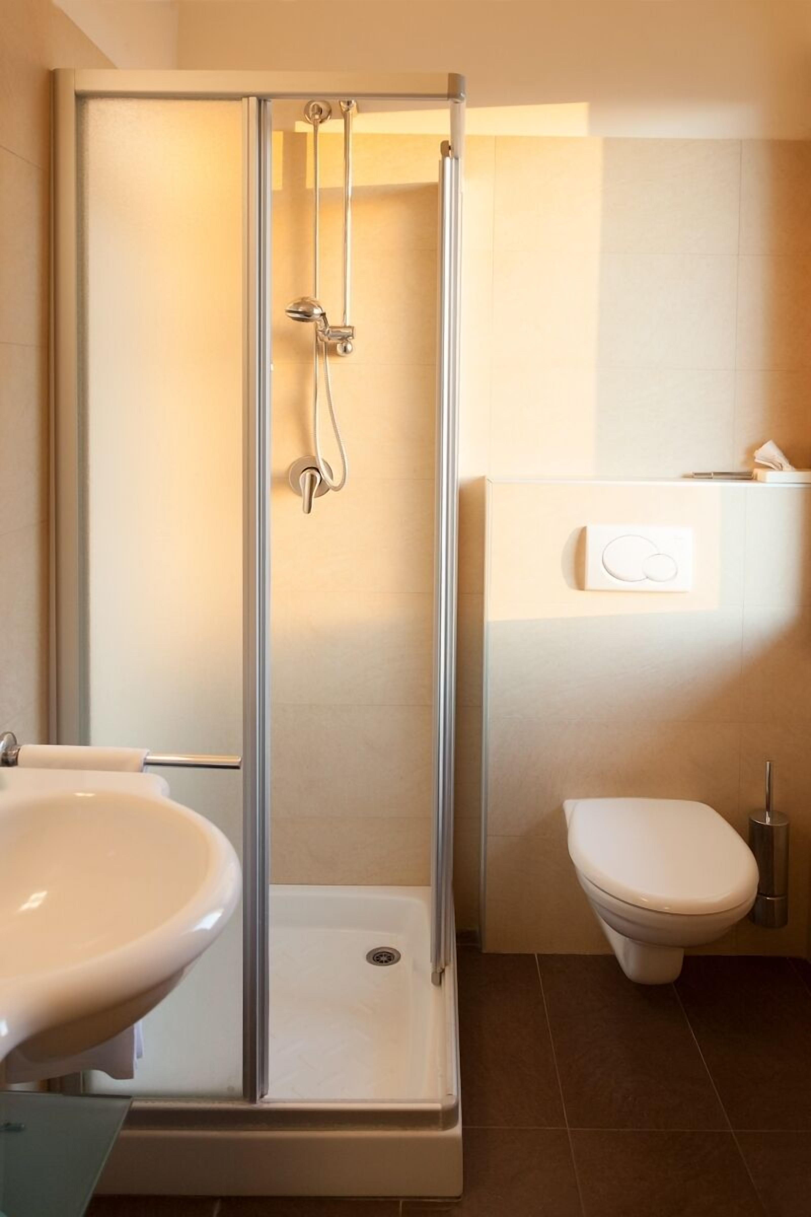 A bathroom with a glass-enclosed shower, a sink, and a toilet.