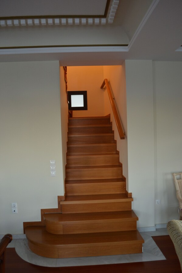 A wooden staircase with a handrail, leading to a landing with a framed picture. - Mikamas Villa (Lesvos)