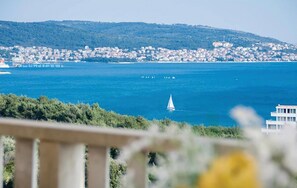 Eine Küstenstadt mit freiem Blick auf das Meer, einem Segelboot und einer entfernten Brücke.