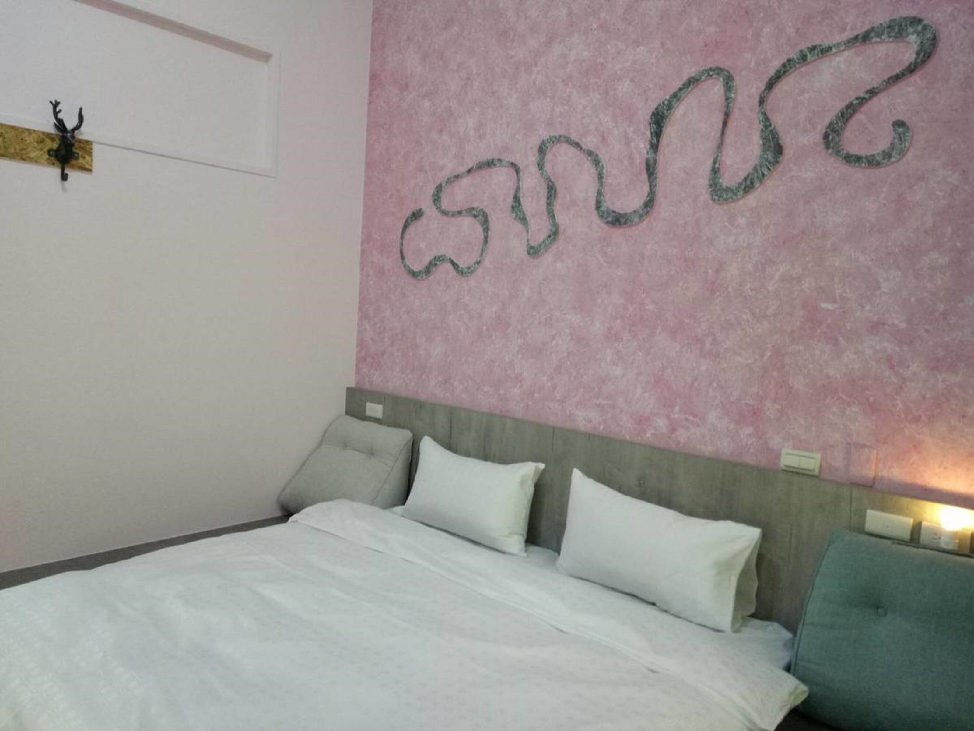 A bedroom with a bed, pillows, a headboard, and a wall with a decorative item.
