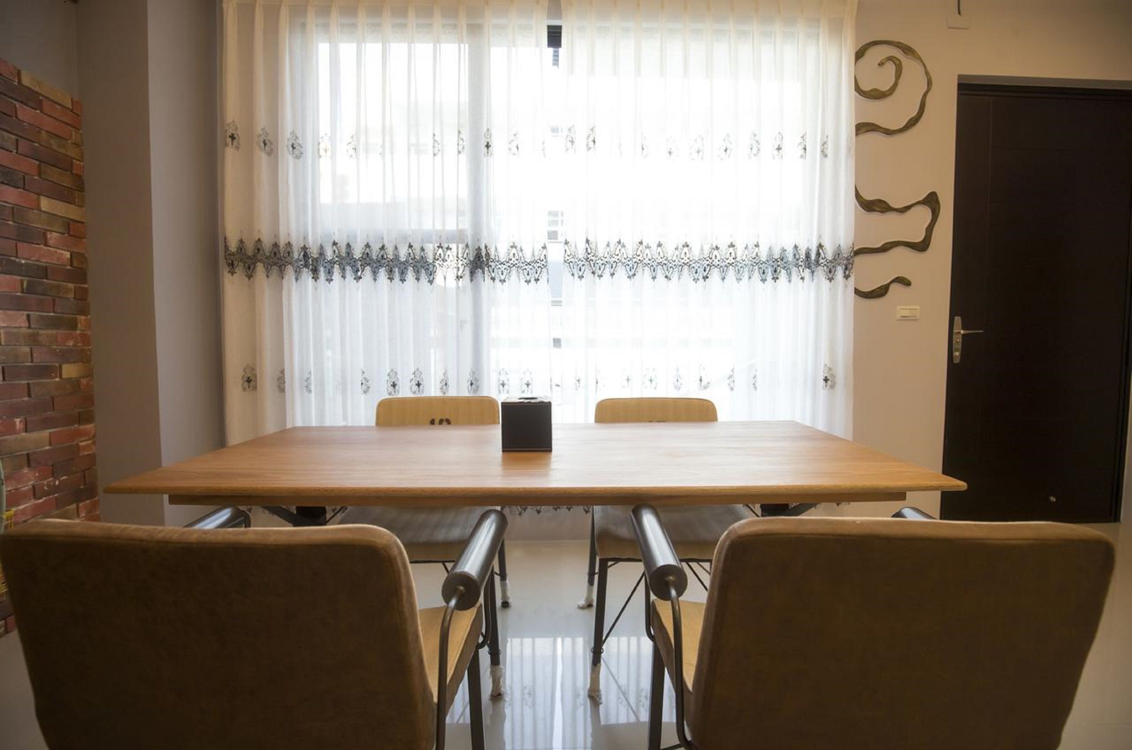 A dining area with a wooden table, four chairs, and a black object on the table.