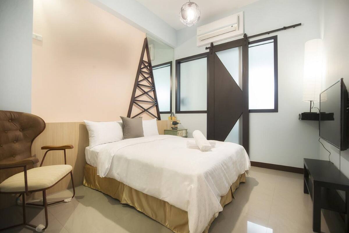 Habitación de hotel con cama, una silla, televisor y ventana con vistas.