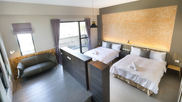 Ein modernes Hotelzimmer mit Balkon, einer Sitzecke, zwei Betten und einem großen Fenster.