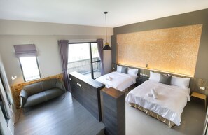 Una habitación de hotel moderna con balcón, sofá, dos camas y un ventanal grande.