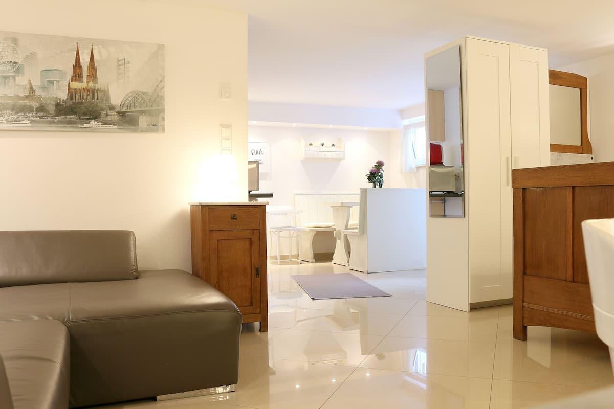 A modern living room with a sofa, a wooden cabinet, and a kitchen area in the background.
