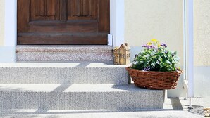 A wooden door with a glass panel and a welcome sign, a small house model, and a basket of flowers on the steps. - Ferienhaus Domblick Herkenrath (Bergisch Gladbach)