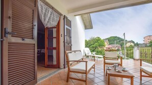 Ein Balkon mit Holztisch und -stühlen, Blick ins Viertel und eine verschlossene Tür mit Fenster.