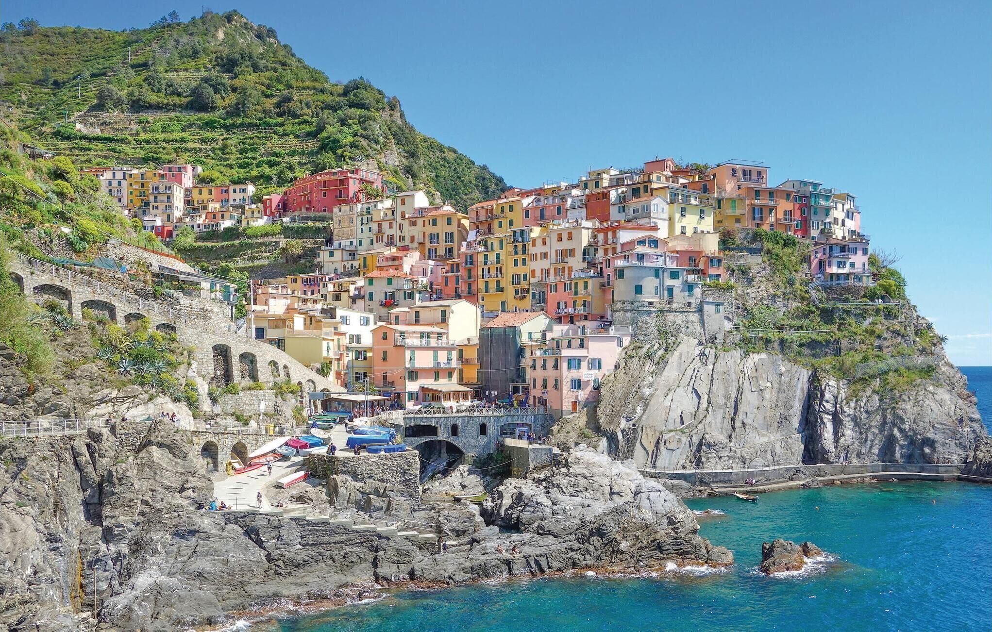 A coastal town with colorful buildings, a stone bridge, and clear blue waters.