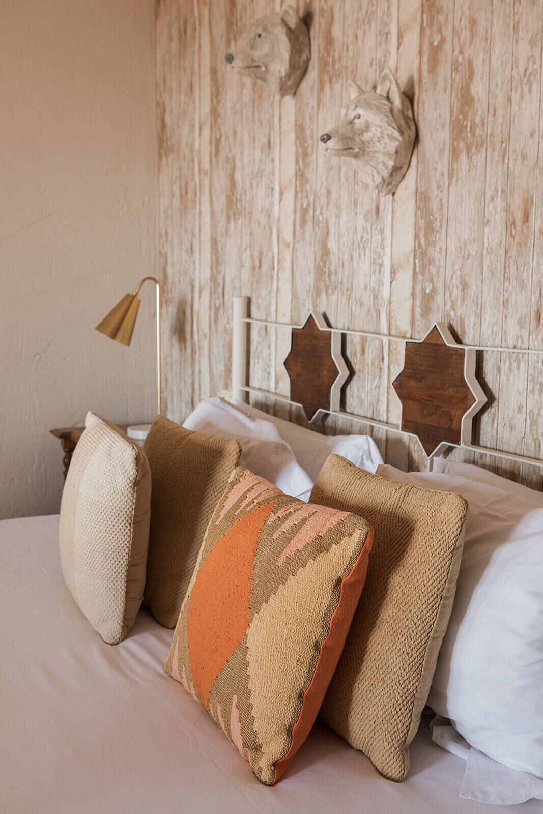 Ein Bett mit Kopfteil, das Tierköpfe zeigt, eine Lampe und mehrere Kissen.