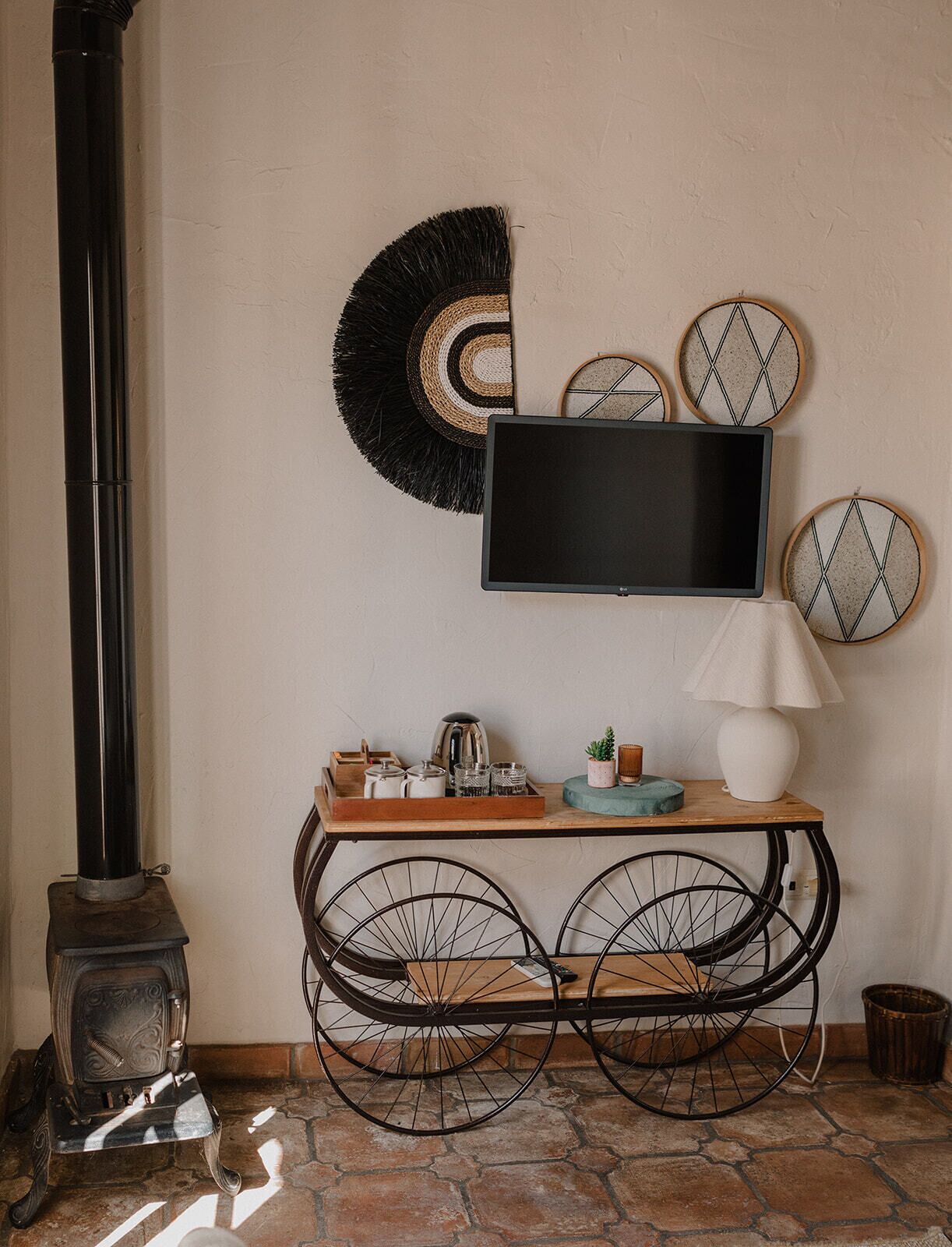A cozy room with a vintage stove, a wooden console table with a TV, and decorative wall art.