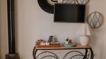 A cozy room with a vintage stove, a wooden console table with a TV, and decorative wall art.