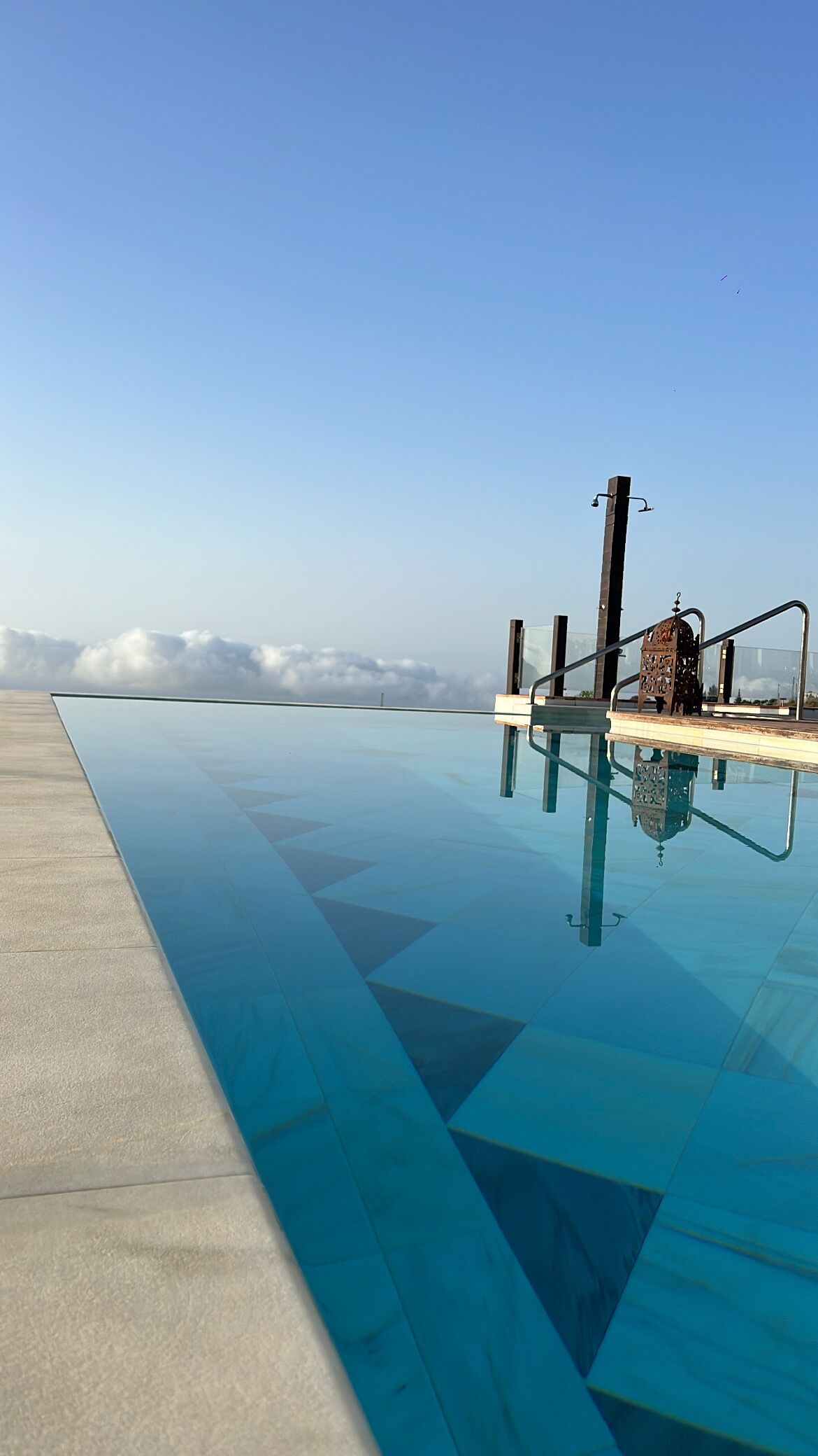 Una piscina infinita azul cristalina con vistas a nubes y un cielo despejado.
