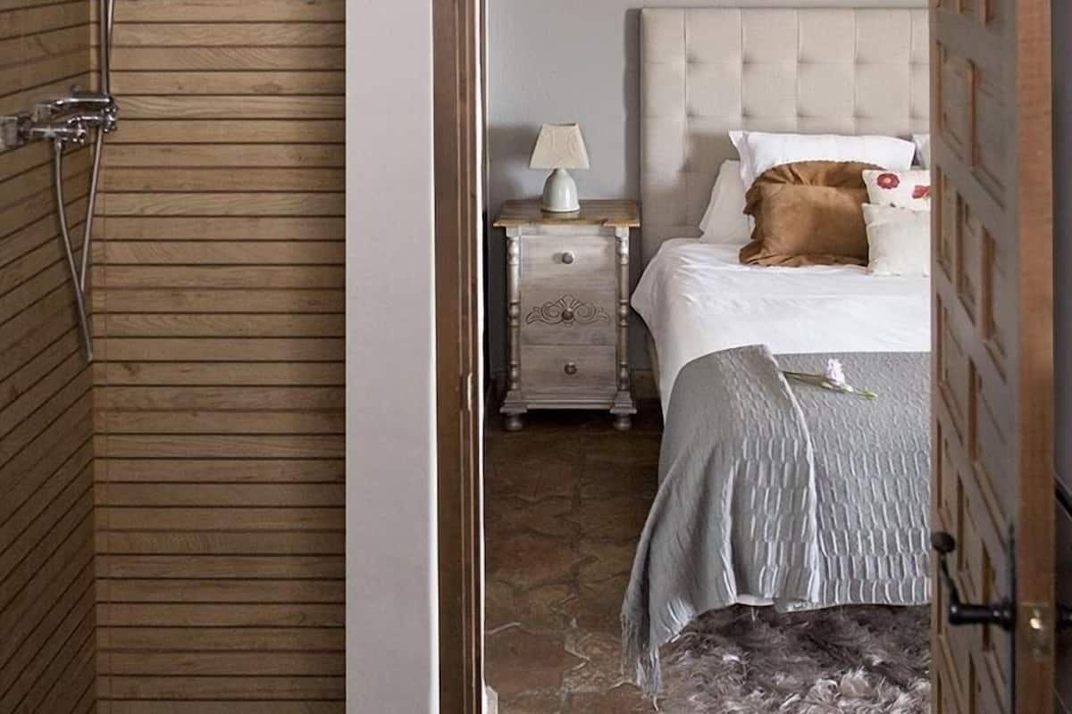 Un dormitorio con cama, mesita de noche, lámpara y puerta de madera.