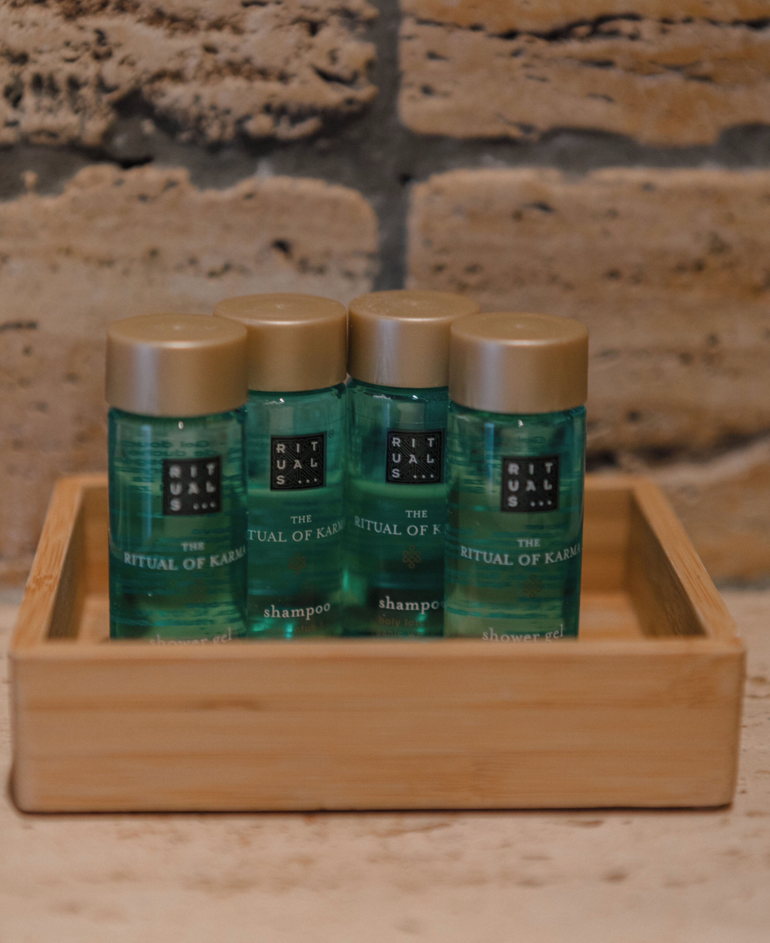 Una bandeja de madera con cuatro botellas de champú 'The Ritual of Karma'.