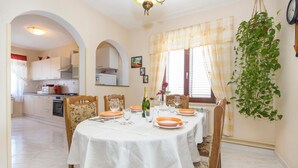 A dining area with a table set for four, chairs, a chandelier, and a hanging plant. - Beautiful home in Labin (Labin)