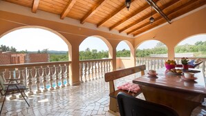 A covered outdoor dining area with a wooden ceiling, white balustrade, and a view of greenery and buildings in the background. - Beautiful home in Labin (Labin)