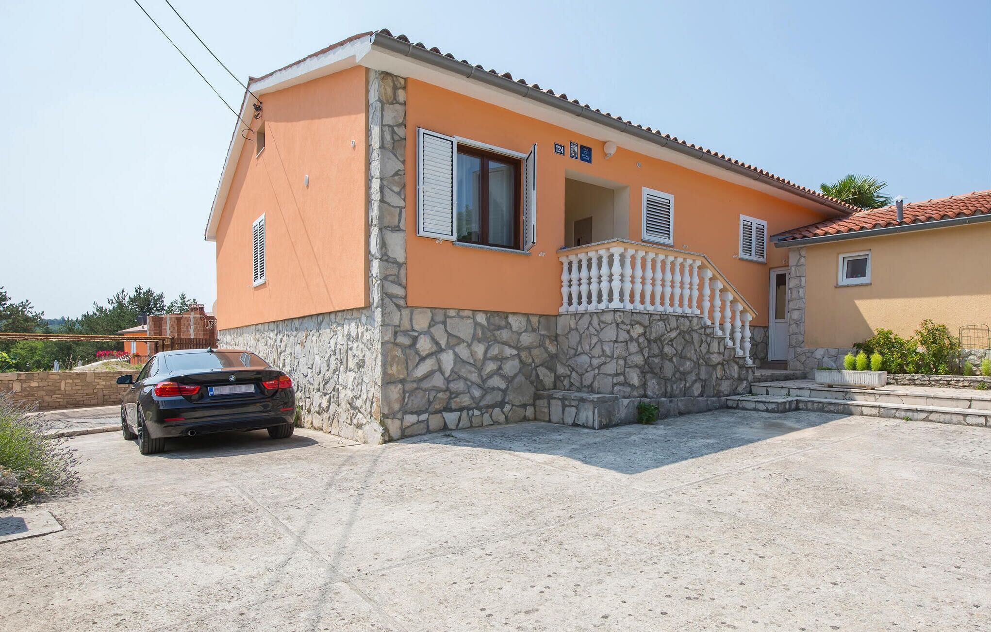A two-story house with a stone facade and a balcony.