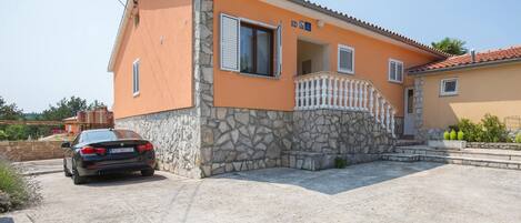 A two-story house with a stone facade and a balcony.