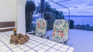 Un área de comedor al aire libre con mesa y sillas, vista al mar y una estructura de pérgola.