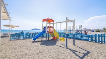 Enjoy a fun-filled day at the beach with a playground featuring a slide and swings.