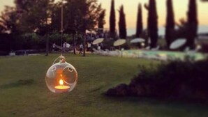 A clear glass lantern with a lit candle on a grassy area. - B&B Radici24 (Battipaglia)