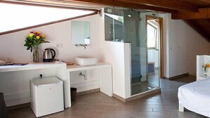 A modern bedroom with a wooden ceiling, a white vanity, a small refrigerator, a glass shower enclosure, and a bed. - B&B Radici24 (Battipaglia)