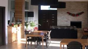 A modern living room with a dining area, a fireplace, and a large black pendant light. - B&B Radici24 (Battipaglia)
