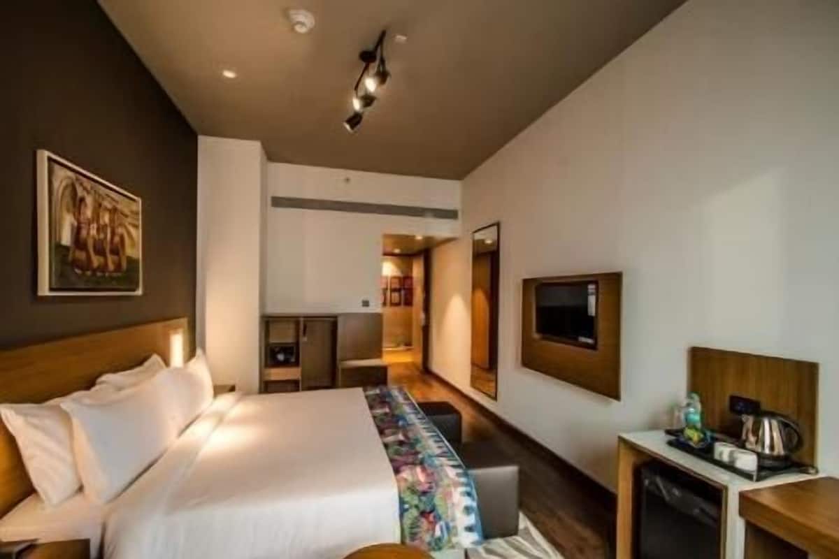 Une chambre d’hôtel équipée d’un lit, d’une table de chevet, d’une télévision et d’un petit coin cuisine.