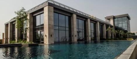 A modern building with large windows and a swimming pool in front.