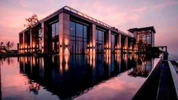 A modern building with large windows and a reflective pool in front.