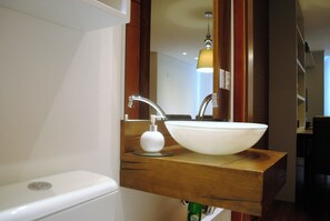 Une salle de bain avec un lavabo blanc, un meuble-lavabo en bois et un miroir.