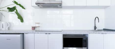 Una cocina moderna con armarios blancos, un microondas integrado y una campana extractora de acero inoxidable.