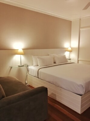 A neatly arranged bedroom with a bed, two bedside lamps, a bedside table, and a chair. - Paradise Motel Busselton (Busselton)