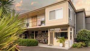 A two-story residential building with a balcony, a covered porch, and a small garden area. - Paradise Motel Busselton (Busselton)