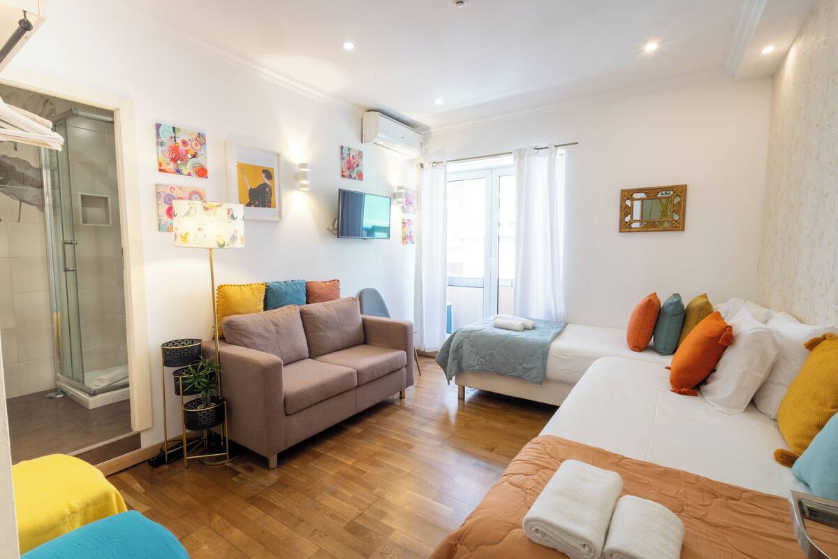Une chambre d’hôtel moderne équipée d’un canapé, d’un lit, d’une petite table, d’une télévision et d’un espace douche.