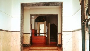 A marble staircase leading to a dark interior space, with a metal gate on the right. - Guesthouse Sweet Liberdade (Lisbon)
