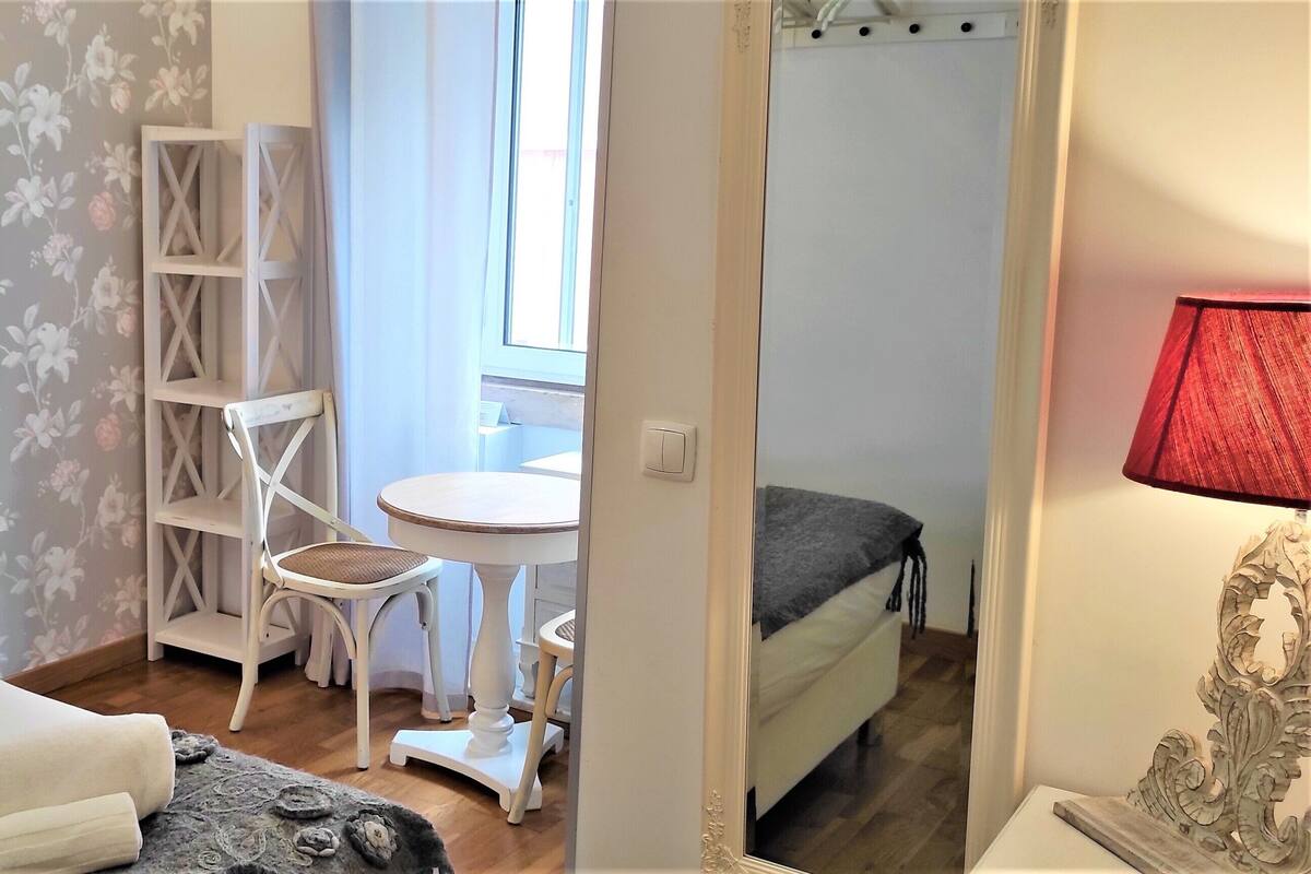 Une chambre à coucher comprenant un lit, une table de chevet, une lampe, une chaise, une petite table et une armoire.