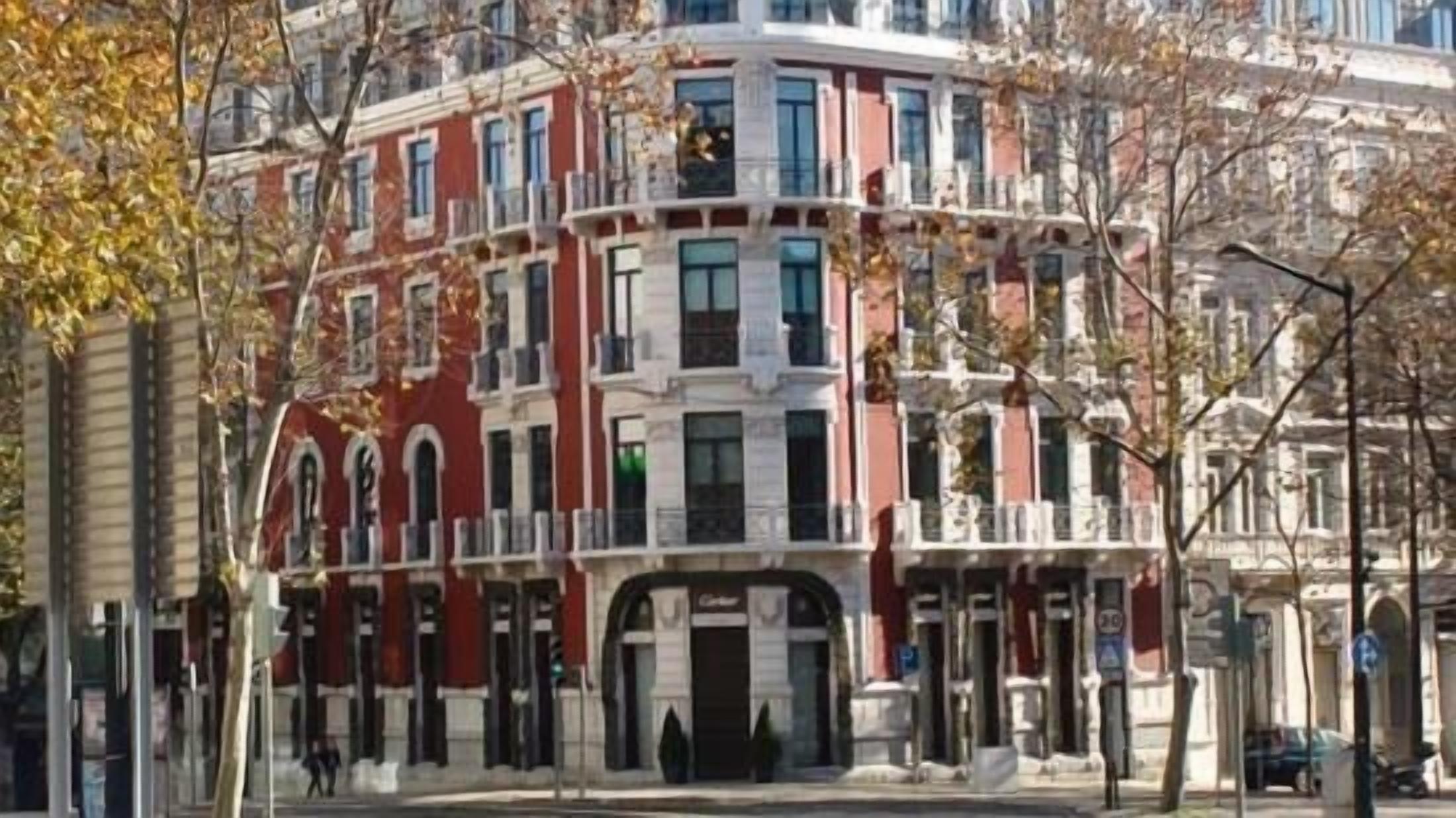 A multi-story building with a classic architectural style, featuring a central entrance with a black door and a balcony on the second floor.