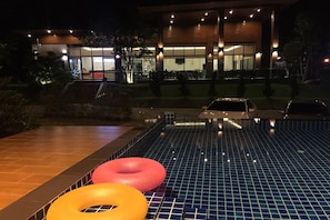 A swimming pool with a tiled deck and two inflatable rings. - Nutchana Hill Boutique Hotel (Hat Yai)