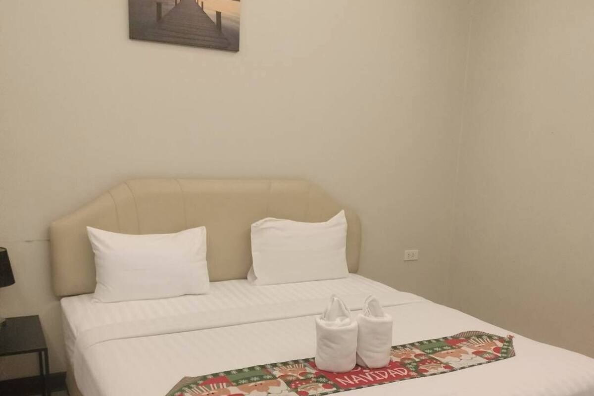 A neatly made bed with white linens and a festive holiday-themed runner.