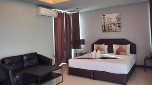 A modern hotel room with a bed, a leather sofa, a coffee table, and a painting on the wall. - Nutchana Hill Boutique Hotel (Hat Yai)