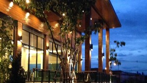 A modern building with a glass facade, outdoor seating, and a well-maintained garden with rocks and pathways. - Nutchana Hill Boutique Hotel (Hat Yai)