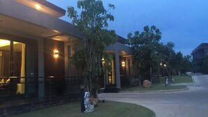 A modern hotel with a well-lit entrance, large windows, and a landscaped front yard. - Nutchana Hill Boutique Hotel (Hat Yai)