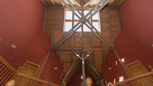 A room with a high wooden ceiling and a large window. - Ostsee-Landhaus (Bastorf)