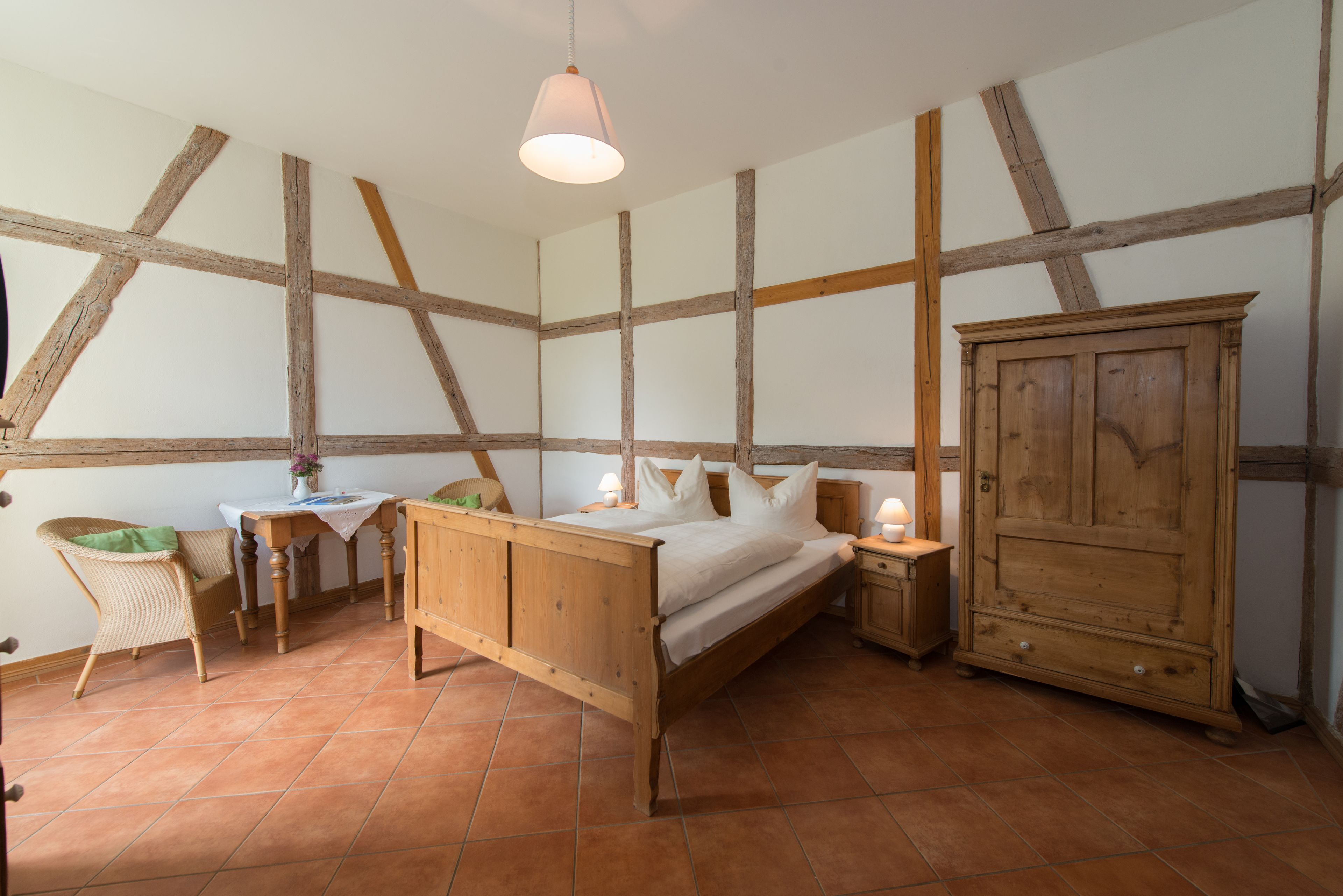 Une chambre à coucher avec un lit en bois, une table de chevet, une armoire, une chaise et une table avec une lampe.