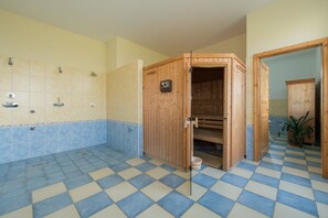 A bathroom with a checkered floor, wooden sauna, and a tiled shower area.
